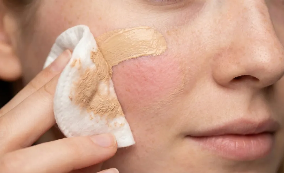 Žena odstraňujúca make-up z líca vatovým tampónom pri nerovnomernej vrstve líčenia